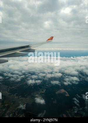 « Vue de l'aile d'avion au-dessus des couches nuageuses et des terres agricoles en patchwork, capture d'un voyage en haute altitude au-dessus d'un paysage couvert » Banque D'Images