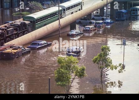 Nouvelle-Orléans, LOUISIANE, États-Unis - août 2005 : un bateau secourant les victimes des inondations passe devant la rampe du Superdome et stationne des voitures sur Poydras Street inondée et des bus d'évacuation alignés sur la rampe du Superdome. Cette photo a été prise avec un appareil photo 35 mm après le passage de l'ouragan Katrina et l'échec des digues du corps des ingénieurs de l'armée américaine, inondant la majeure partie de la ville. Banque D'Images