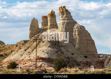 De grandes formations hoodoo surplombent un affleurement rocheux près d'une route et de lignes téléphoniques ou électriques dans le paysage aride du sud-ouest de l'Utah, aux États-Unis Banque D'Images