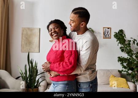 Un couple joyeux profite d'un moment d'amour, vêtu de pulls confortables à la maison pendant l'hiver. Banque D'Images