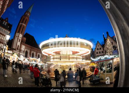 26 novembre 2024, Hesse, Francfort-sur-le-main : un carrousel tourne au marché de Noël de Francfort devant l'Alte Nikolaikirche sur le Römerberg (tourné avec une longue exposition et un objectif grand angle extrême). Photo : Boris Roessler/dpa Banque D'Images