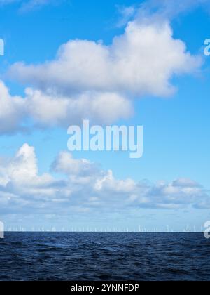 Nuage blanc et ciel bleu au-dessus du parc éolien offshore de Gwynt y Môr à l'horizon dans la mer d'Irlande près de Llandudno, pays de Galles. Banque D'Images