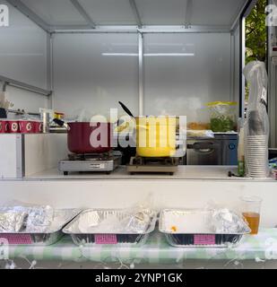 Intérieur de cuisine de petite stalle de nourriture, équipement de cuisine et de service. Deux grandes casseroles sur des brûleurs portables, des ingrédients et des plateaux de service et des tasses Banque D'Images