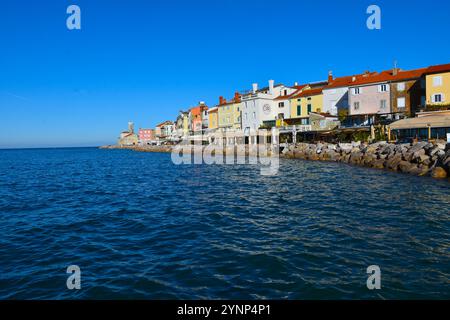 Piran, Slovénie - 16 novembre 2024 : bâtiments sur la côte de la mer Adriatique et phare dans la ville de Piran en Istrie et région du littoral, Slovénie Banque D'Images