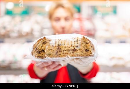 Erfurt, Allemagne. 26 novembre 2024. Une vendeuse présente un stollen au marché de Noël d'Erfurt. Crédit : Jacob Schröter/dpa/Alamy Live News Banque D'Images