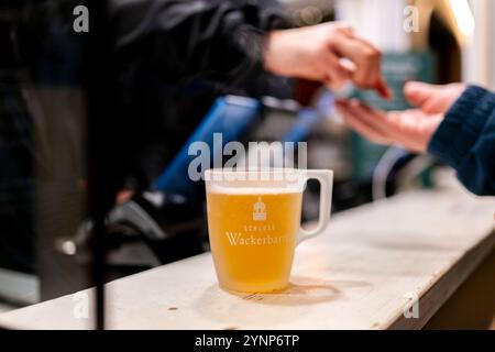 Erfurt, Allemagne. 26 novembre 2024. Un vendeur sert un vin chaud blanc au comptoir du marché de Noël d'Erfurt. Crédit : Jacob Schröter/dpa/Alamy Live News Banque D'Images