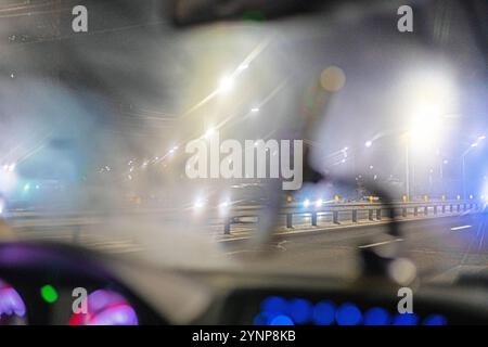 pare-brise de voiture embué dans les lumières du soir pendant la conduite. Mauvaise visibilité sur la route Banque D'Images