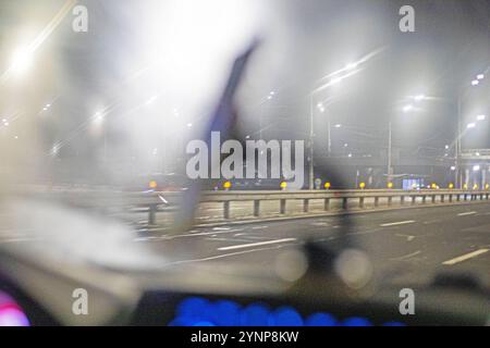 pare-brise de voiture embué dans les lumières du soir pendant la conduite. Mauvaise visibilité sur la route Banque D'Images