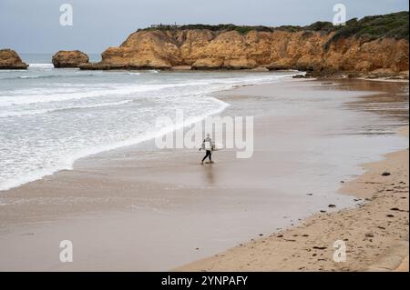 29.10.2024, Torquay, Victoria, Australie - Ein surfer geht mit seinem Surfbrett unterm Arm am Strand von Torquay Beach entlang. Tourquay Beach ist ein beruehmter und Beliebter Ort fuer Wellenreiter in australien und bekannt fuer Seine Surfkultur, zudem Gruendungsort der Kultmarken Rip Curl und Quicksilver. Ausserdem markiert die Kuestenstadt den Beginn der Great Ocean Road. *** 29 10 2024, Torquay, Victoria, Australie Un surfeur marche avec sa planche de surf sous le bras le long de Torquay Beach Tourquay Beach est un endroit célèbre et populaire pour les surfeurs en Australie et connu pour sa culture du surf, également th Banque D'Images