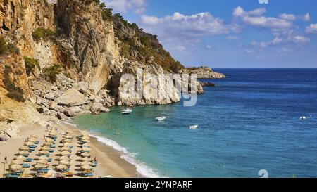 Une plage idyllique avec des eaux bleues et des bateaux, encadrée par des rochers et des parasols par temps ensoleillé, Kyra Panagia, Kyra Panagia Beach, Côte est, Karpathos, à faire Banque D'Images