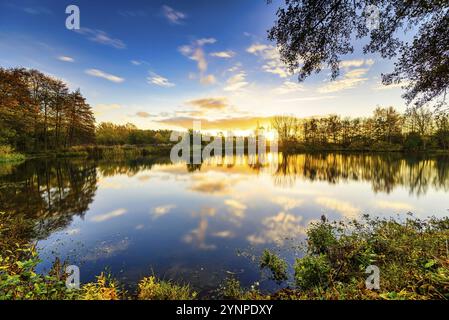 Beau lever de soleil au lac avec réflexion dans l'eau et les nuages en mouvement Banque D'Images
