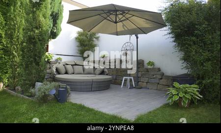 Terrasse de jardin avec groupe salon et parasol dans un coin jardin entouré d'un arbre colonnaire Banque D'Images