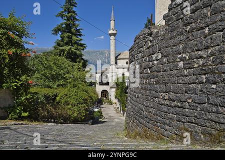 Au premier plan, un mur de briques robuste se tient ferme, tandis qu'à l'arrière-plan, un grand et élégant minaret atteint le ciel, appartenant à la mosquée de GJ Banque D'Images