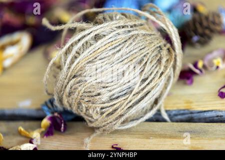 Gros rouleau de ficelle de jute brune pour l'artisanat couché sur une table en bois. Loisirs et thème des matériaux d'artisanat Banque D'Images