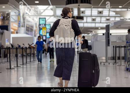 Voyageur avec un sac à dos et une valise dans un terminal d'aéroport très fréquenté Banque D'Images