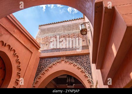 Vue extérieure de la Madrasa Ben Youssef avec une arche et des détails ocres ornées à Marrakech, Maroc Banque D'Images