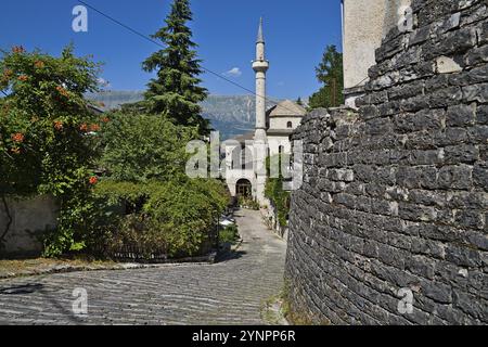 Au premier plan, un mur de briques robuste se tient ferme, tandis qu'à l'arrière-plan, un grand et élégant minaret atteint le ciel, appartenant à la mosquée de GJ Banque D'Images