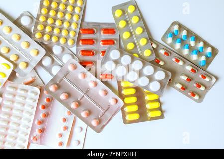 Diverses capsules de médicaments, comprimés sont répartis sur la surface blanche, mettant en valeur différentes formes collection met en évidence la diversité dans les produits pharmaceutiques. Banque D'Images