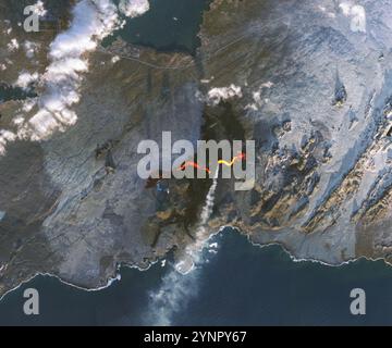 Grindavik, Islande. 24 novembre 2024. Des crues de lave et de fumée provenant d’une fissure éruptive près du pic Stóra Skógfell du système volcanique Sundhnúkur sur la péninsule de Reykjanes dans le sud-ouest de l’Islande, le 24 novembre 2024 près de Grindavik, Islande. Une langue de lave coulait sur le parking du célèbre spa Blue Lagoon à gauche de l’image. Crédit : Michala Garrison/NASA/Alamy Live News Banque D'Images