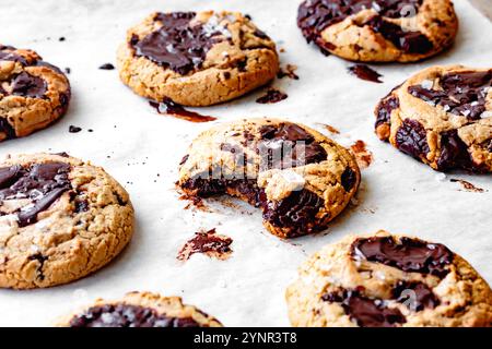 Un assortiment de biscuits fraîchement cuits avec des morceaux de chocolat gooey sur un papier parchemin. Banque D'Images