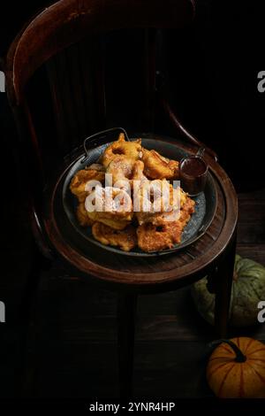 Beignets à la citrouille, plat sucré espagnol, Buñuelos de calabaza, la receta tradicional valenciana, chaise en bois. Le fond sombre, thème automnal, grand pum Banque D'Images