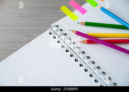 Crayons de couleur sur une partie d'un cahier en spirale et marqueur coloré sur un bureau gris, travail créatif ou fournitures scolaires, espace de copie, Focus sélectionné, narro Banque D'Images