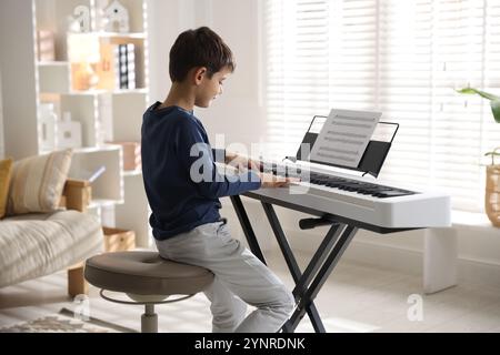 Petit garçon jouant au synthétiseur à la maison. Instrument de musique électronique Banque D'Images