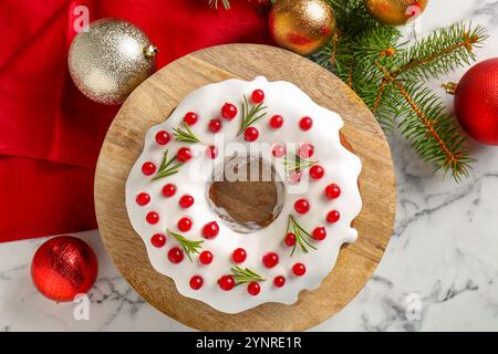 Gâteau de Noël joliment décoré, branches de sapin et boules sur la table en marbre blanc, plat Banque D'Images