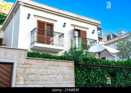Une charmante villa de style méditerranéen avec balcons et un jardin luxuriant, mettant en valeur un design élégant et une vie en plein air tranquille. Banque D'Images