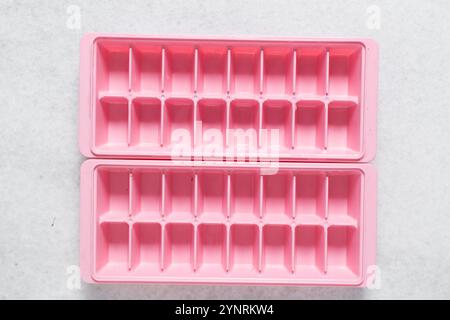 Vue aérienne du bac à glaçons rose avec un couvercle, vue de dessus des bacs à glaçons roses à la mode sur un comptoir en marbre blanc Banque D'Images