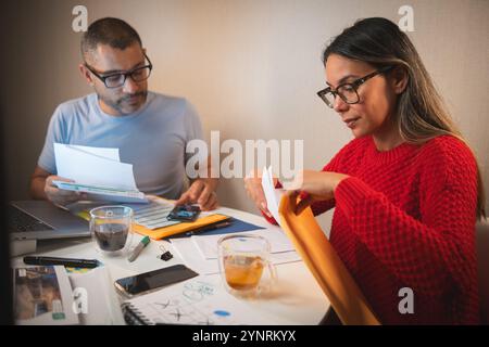 Un homme et une femme sont assis à une table avec des papiers et une tasse de café Banque D'Images