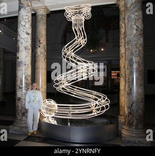 Londres, Royaume-Uni. Artiste Anna Lomax avec sa sculpture en tube néon intitulée All Illit Up au Victoria & Albert (V&A) Museum de Londres. Inspiré par la saison des fêtes, Lomax a une colonne torsadée de forme organique au lieu d'un sapin de Noël. Il s'agit de comparer directement le rôle des arbres dans le monde naturel pour représenter la force par rapport aux colonnes et leur rôle dans la construction de bâtiments. Tous éclairés se trouvent à l'entrée du musée. 25 novembre 2024. Steve Bealing/Landmark Media WWW.LMKMEDIA.COM Banque D'Images