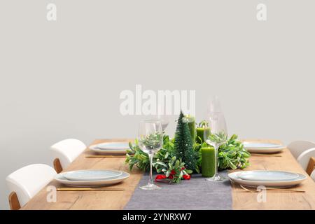 Table de Noël avec couronne de gui, verres et bougies dans la salle à manger Banque D'Images