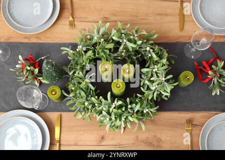 Table de Noël avec couronne de gui, verres et bougies, gros plan Banque D'Images