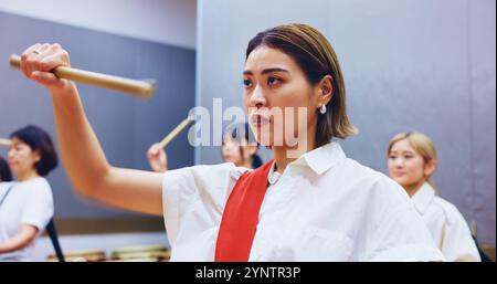 Japonais, batterie et femme en pratique pour la musique sur instrument pour la performance, la créativité ou la classe. Taiko, des gens ou des femmes battrices apprenant dans le groupe Banque D'Images