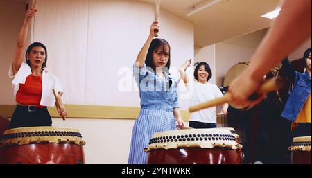 Japonais, tambours et personnes apprenant la musique sur instrument pour la pratique de scène, la performance créative ou le talent. Taiko, femmes et batteurs féminins dans le groupe Banque D'Images