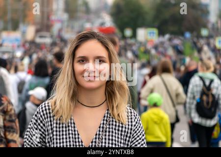 femme seule devant la foule de l'autre côté de la route. Une fille va à l'encontre du mouvement de la foule pendant la journée dans une grande ville. Banque D'Images