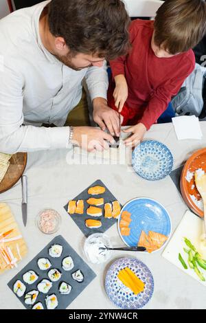 Père et fils préparant des sushis à la maison ensemble Banque D'Images