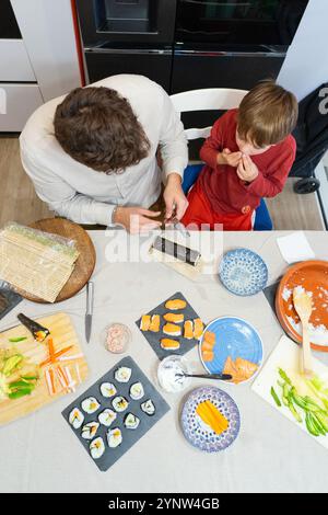 Père et fils caucasiens préparant des sushis faits maison dans la cuisine vue d'en haut Banque D'Images