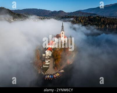 Bled, Slovénie - vue aérienne du magnifique lac de Bled (Blejsko Jezero) avec Église de pèlerinage de l'Assomption de Maria sur une petite île avec Pletna b Banque D'Images