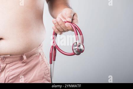 Un homme avec un plus grand physique tient un stéthoscope, se préparant à vérifier sa santé. Cela souligne l'importance des bilans de santé réguliers f Banque D'Images