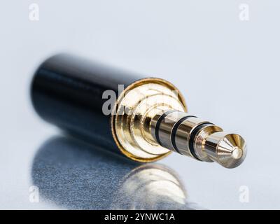 Plan macro du connecteur mini jack plaqué or 4 broches pour le remplacement isolé sur fond blanc avec réflexion Banque D'Images
