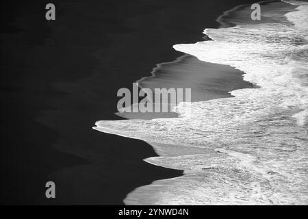 Vagues océaniques noires et blanches sur Black Sand Volcanic Beach - texture graphique minimale Banque D'Images