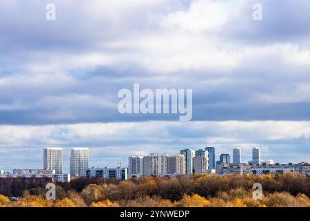 ciel nuageux bleu foncé bas au-dessus du parc de la ville coloré et des maisons de grande hauteur à l'horizon le jour d'automne Banque D'Images