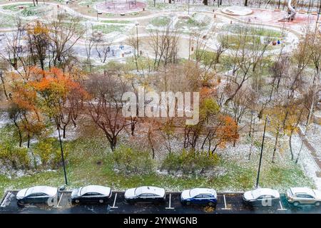 vue aérienne des voitures garées près d'une aire de jeux sportive couverte par la première neige le jour d'automne Banque D'Images