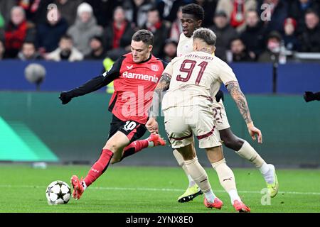 Leverkusen, Allemagne. 26 novembre 2024. Champions League match, Bayer Leverkusen - Salzbourg. Florian Wirtz de Leverkusen (à gauche) et Kamil Pi·tkowski de Salzbourg se battent pour le ballon. Crédit : Federico Gambarini/dpa/Alamy Live News Banque D'Images