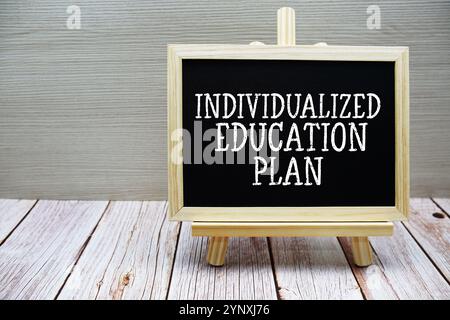 Texte du plan d'éducation individualisé écrit sur tableau noir avec chevalet sur fond en bois Banque D'Images