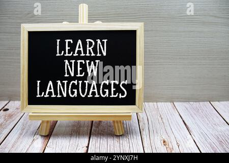 Apprendre de nouvelles langues texte écrit sur tableau avec chevalet sur fond de bois Banque D'Images