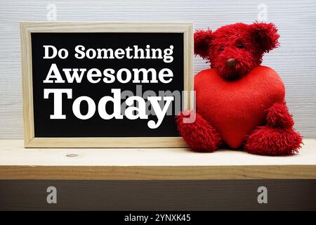 Faites somthing Awesome aujourd'hui Motivational and inspiration citations sur tableau noir avec ours en peluche sur fond de bois Banque D'Images