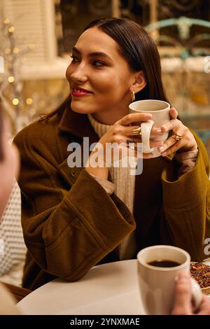 Jeune couple partage le rire et la chaleur autour d'un café dans un café confortable au cours d'un après-midi délicieux. Banque D'Images